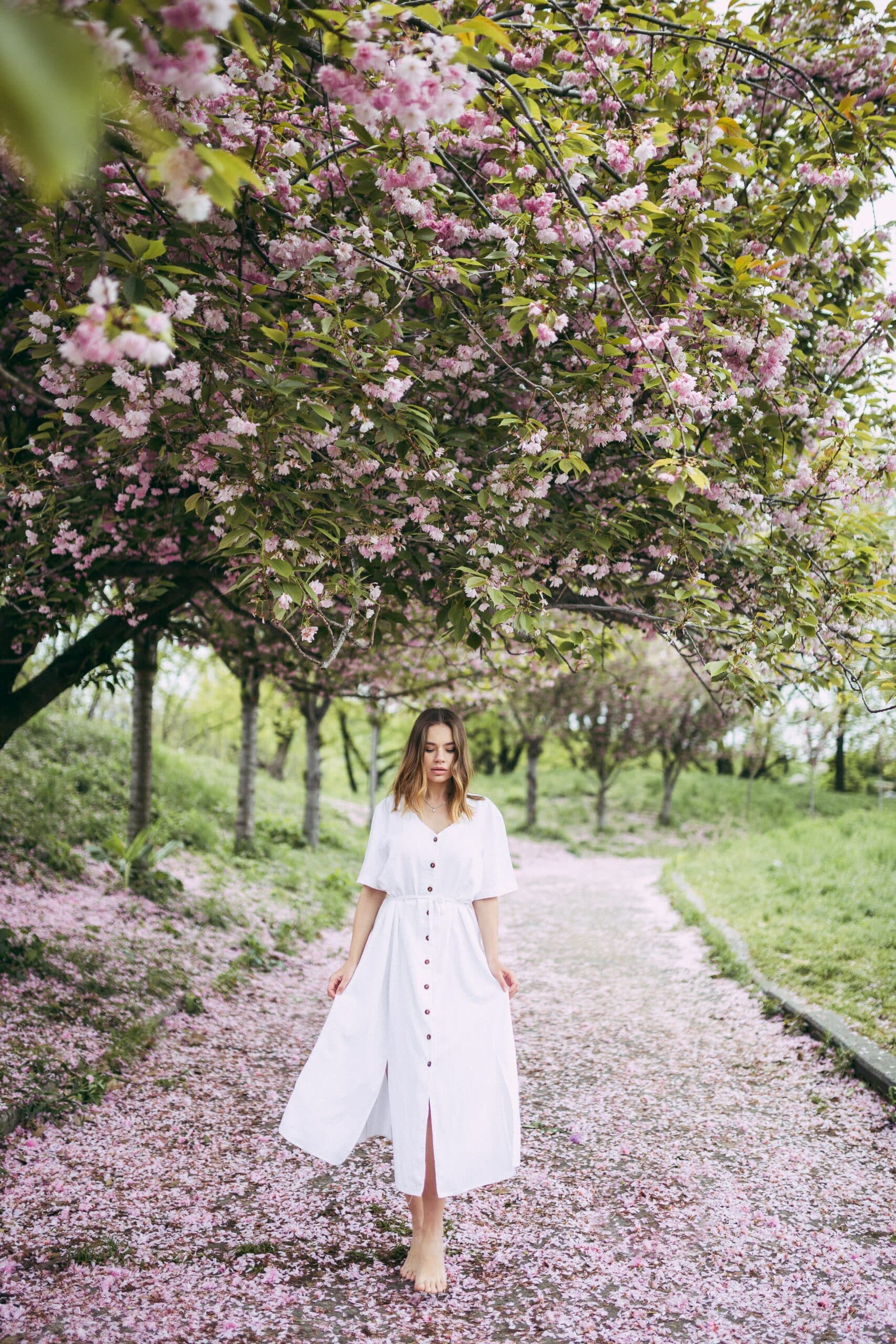 woman wearing white midi dress in cherry blossom trees